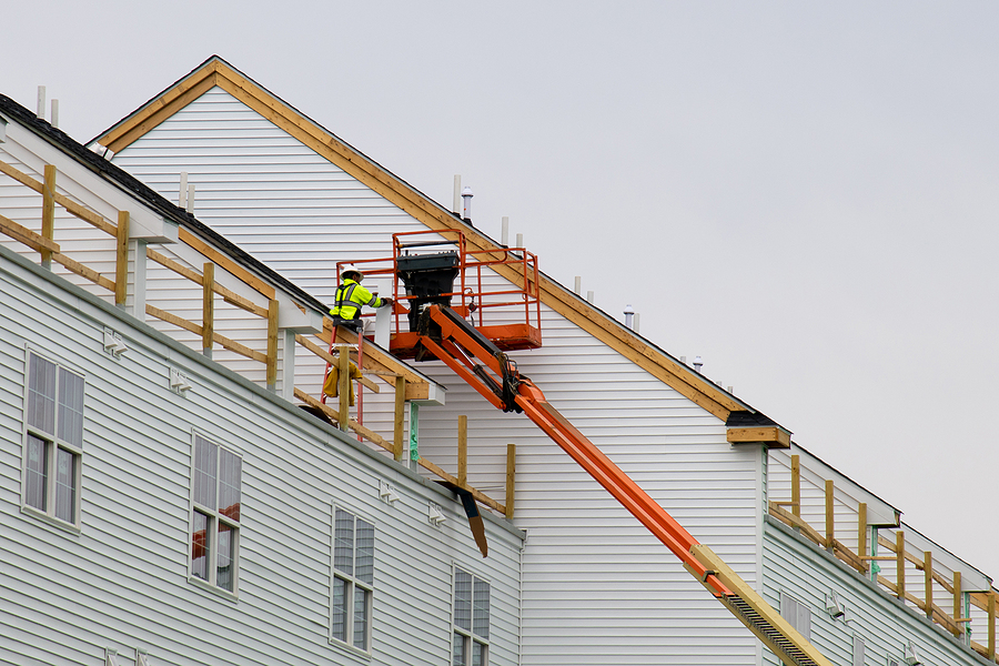 A Worker Installs Panels Siding On The Facade Of The House Wall, Siding Installation